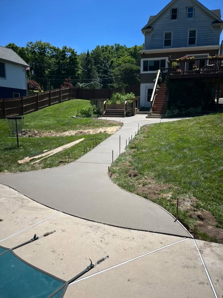 Freshly poured curving concrete walkway from the pool area to the house