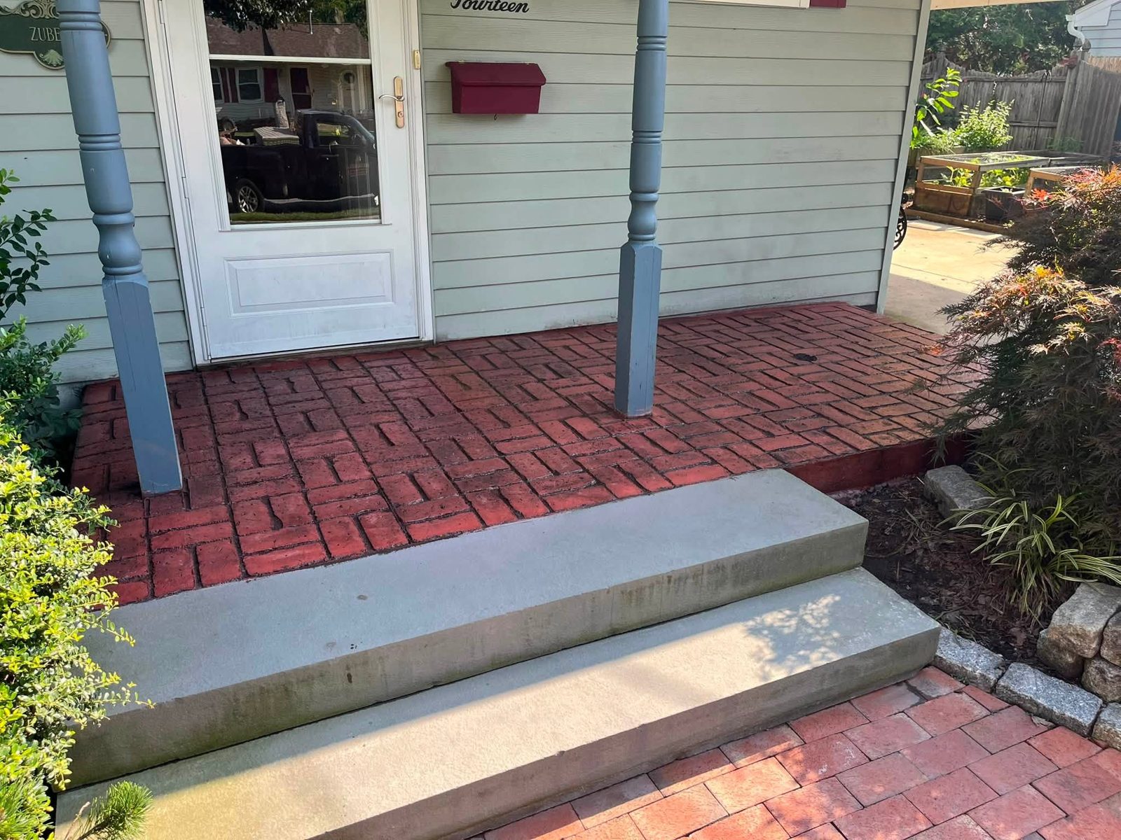 New concrete steps leading up to a red stamped concrete porch