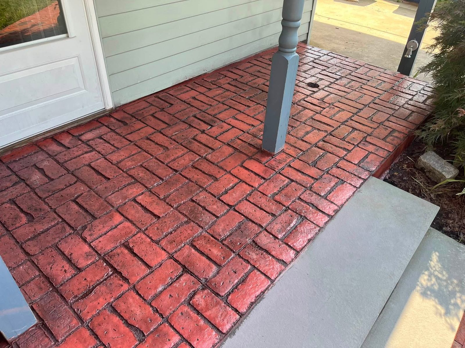Close-up of red herringbone stamped concrete porch and concrete step